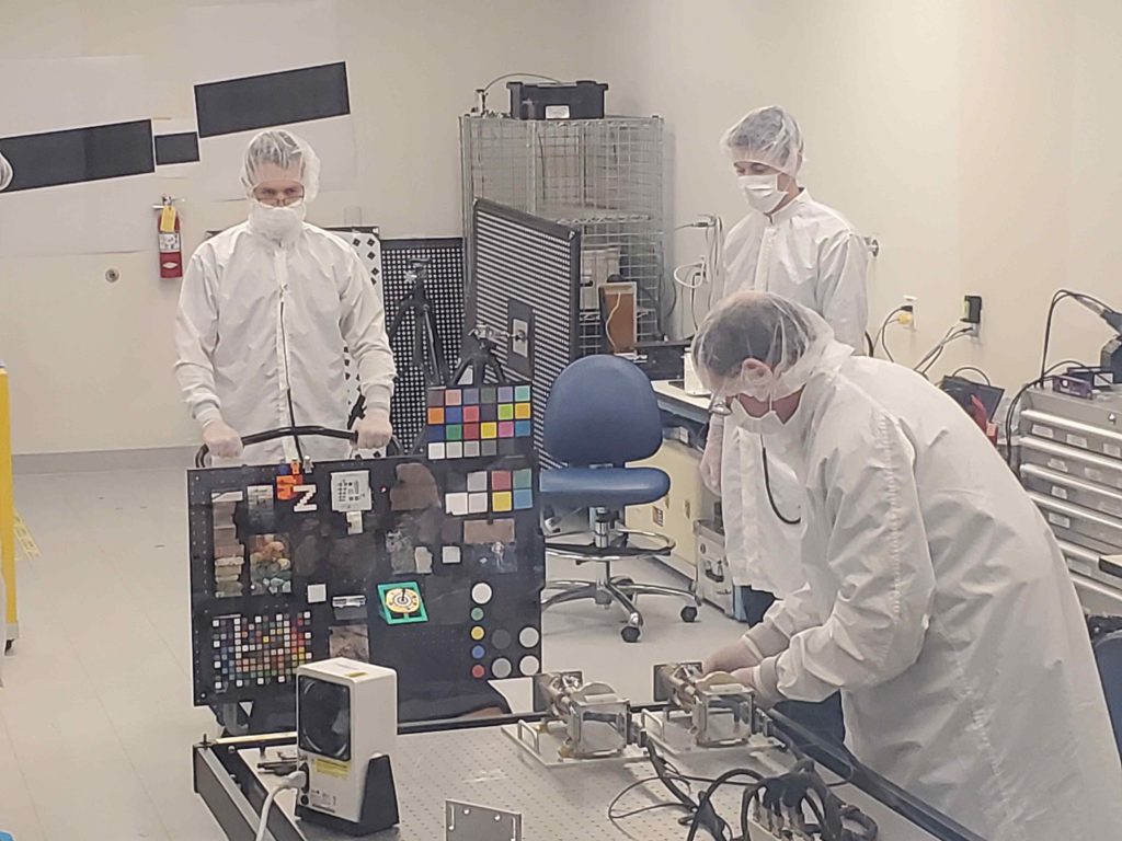 Members of the Mars 2020 Perseverance rover Mastcam-Z calibration group in the clean room setting up the “GeoBoard” rock and standards target for imaging by the flight cameras at Malin Space Science Systems in May, 2019.