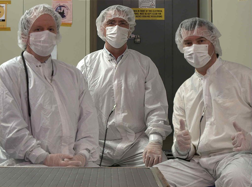 During the functional checkout required as part of delivery of the cameras to the rover at JPL, P.I. Jim Bell (right), Instrument Manager Mike Ravine (middle), and Deputy P.I. Justin Maki (left) pose for a clean room portrait taken with the left Mastcam-Z flight camera.